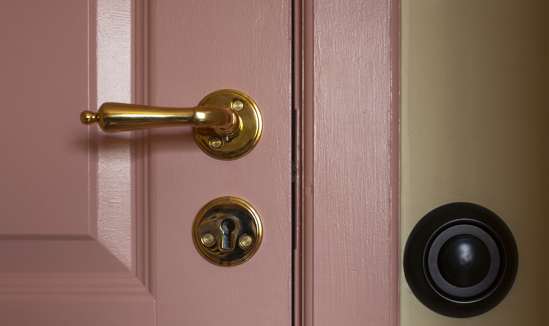 Close-up of brass door handle against pink door